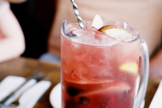 A close up of a glass with blueberry sangria on ice