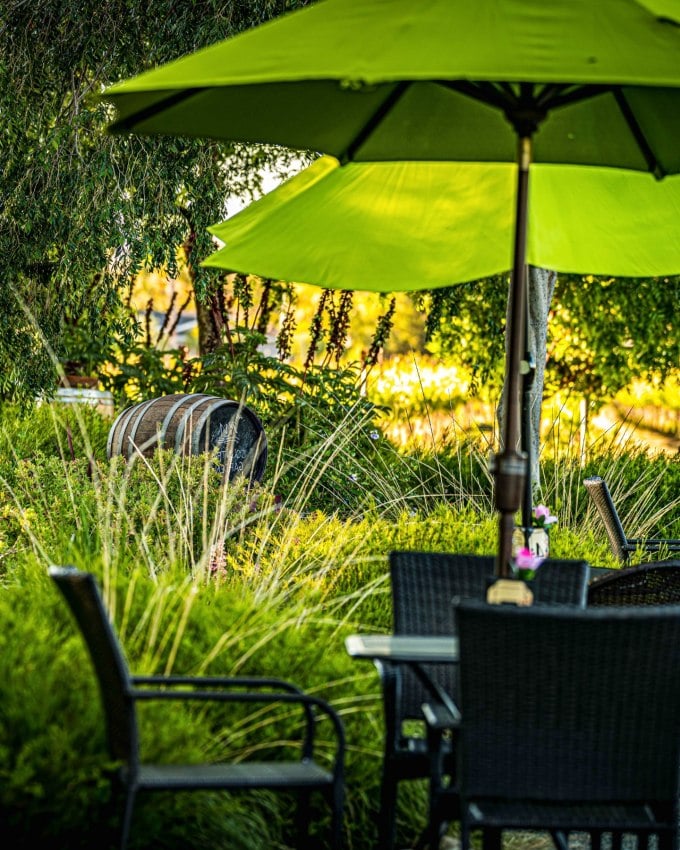 Empty tables in the RM tasting room garden with green umbrellas and a sign with table numbers sitting on top in the morning sunrise