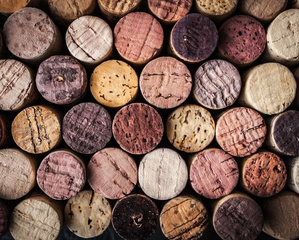 A picture of corks stacked on top of eachother with the ends facing the camera that are stained various shades of light pink to purple from contact with wine in the bottle