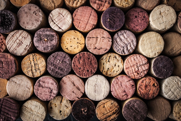 A picture of corks stacked on top of eachother with the ends facing the camera that are stained various shades of light pink to purple from contact with wine in the bottle